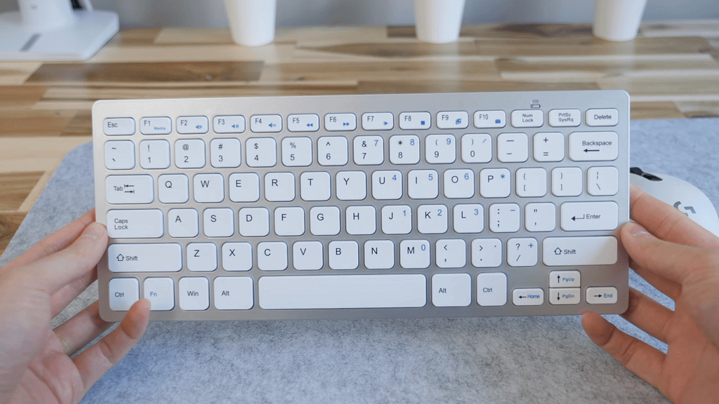 A silver JETech ultra slim keyboard above a grey mouse mat as part of a minimalist home office