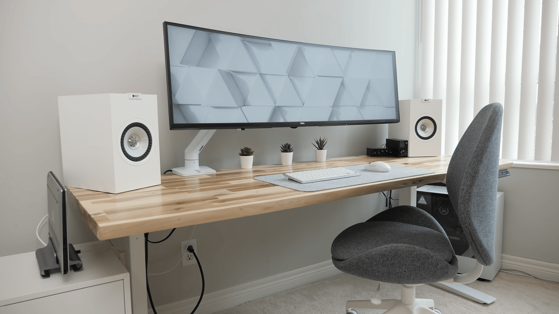 A minimalist home office setup against on a natural wood desk against a white background